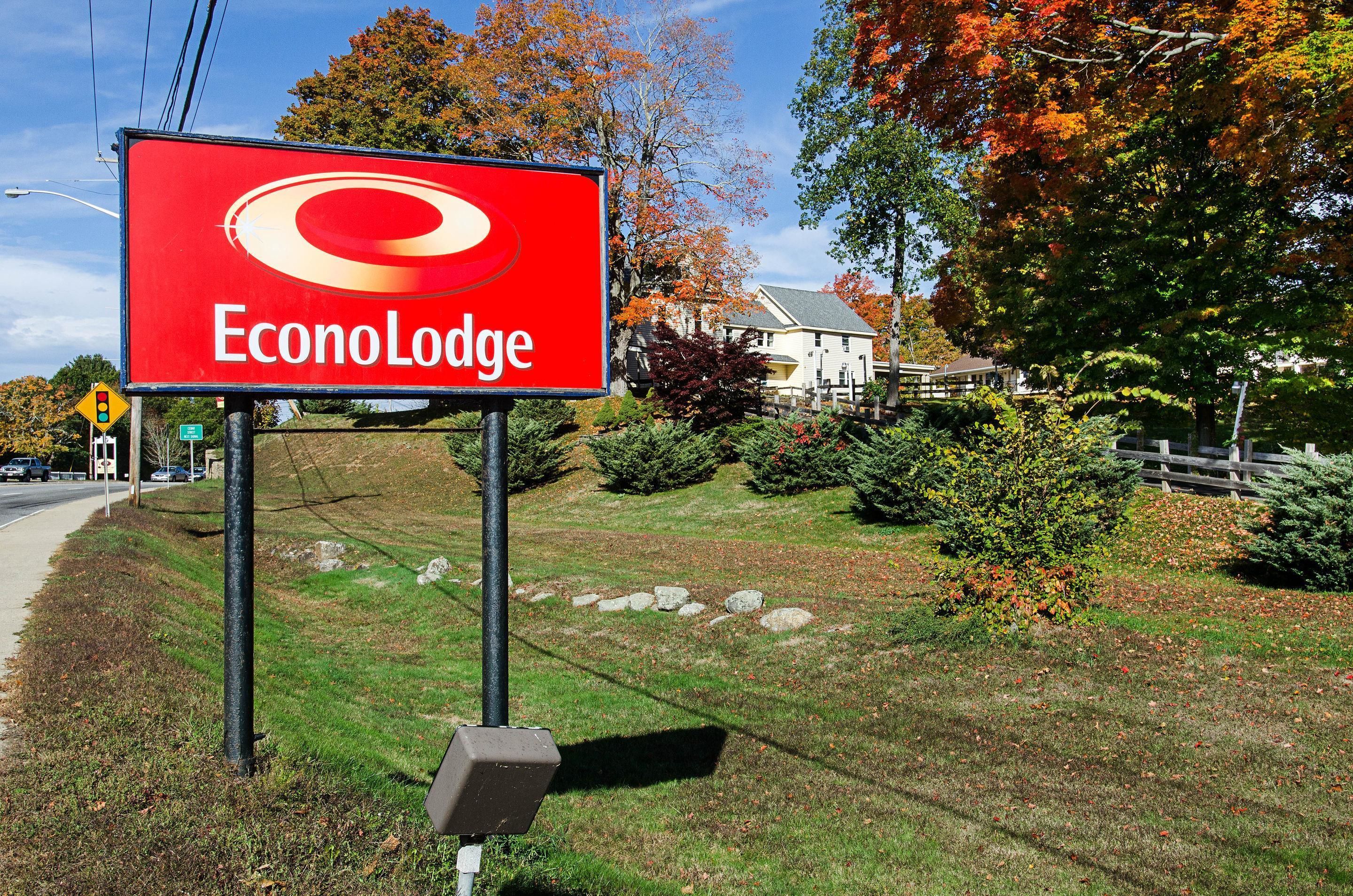 Naamplaatje voor Econo Lodge, met een gazon en bomen op de achtergrond.