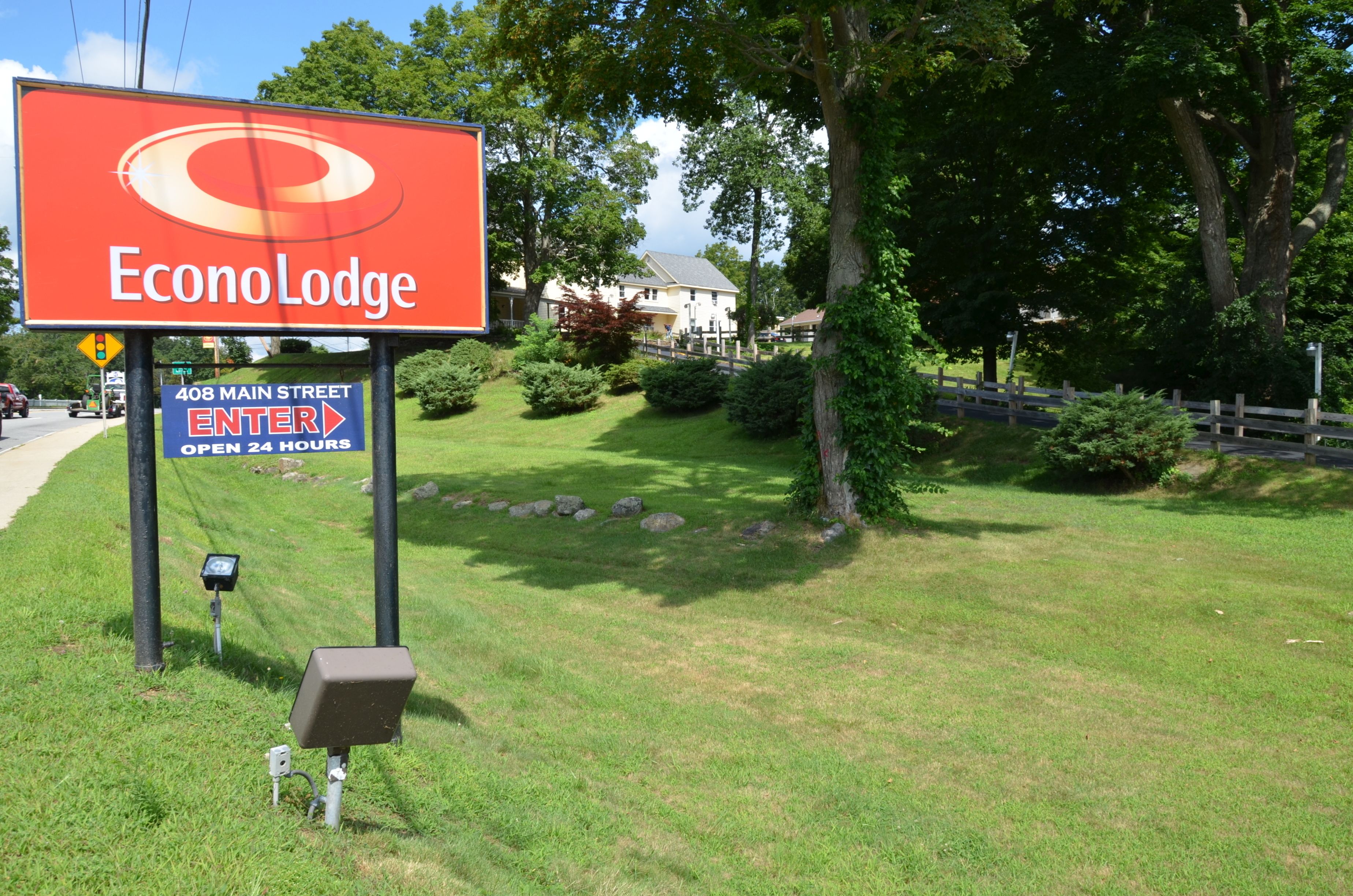 Señal de Econo Lodge con letrero de 'abierto las 24 horas' y una flecha direccional.