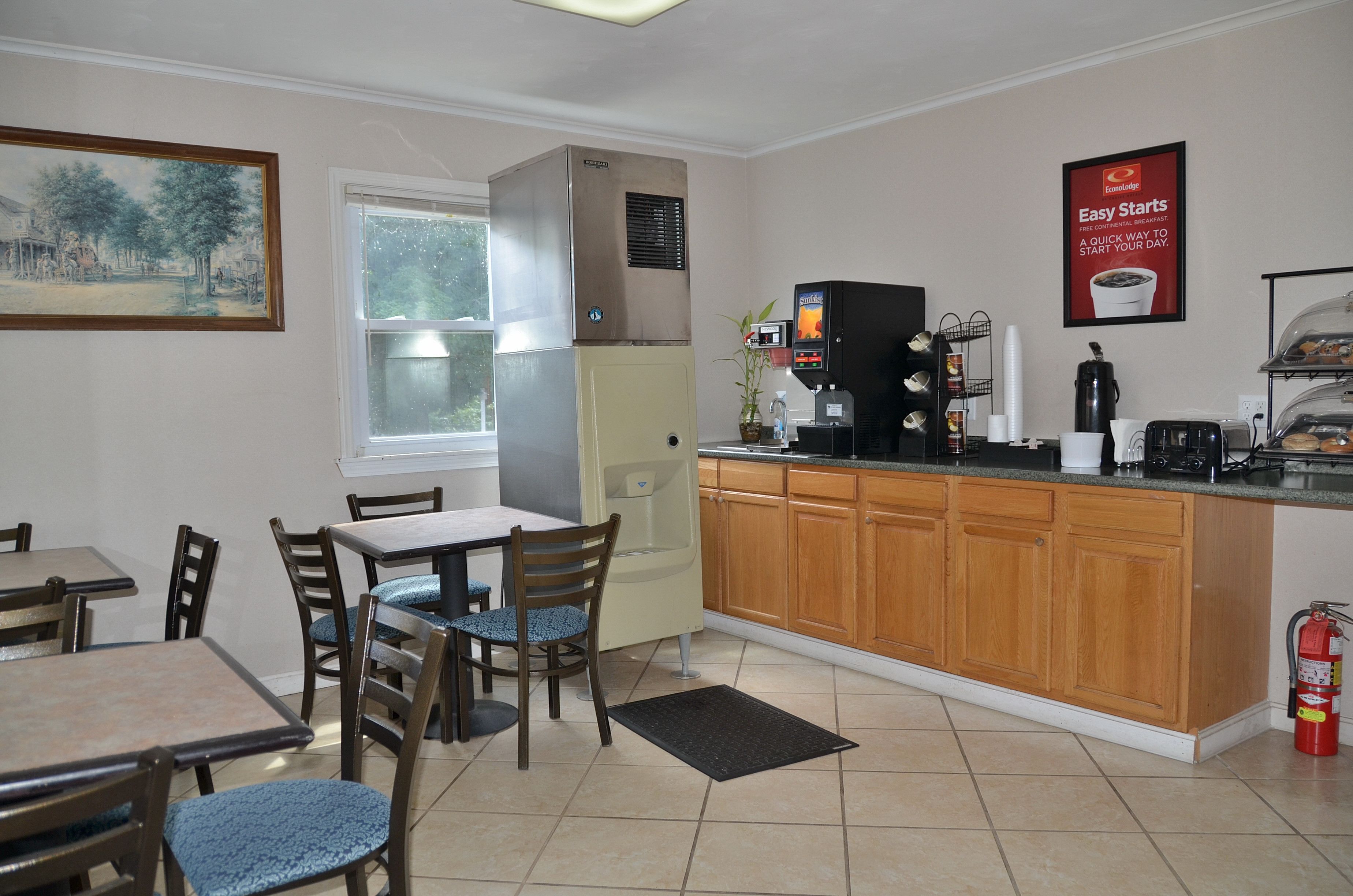 A compact kitchen with a dining area, a coffee machine, and a fire extinguisher.