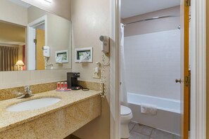 A bathroom with a sink, mirror, hair dryer, and a shower area. - Econo Lodge Sturbridge Route 20 (Sturbridge)