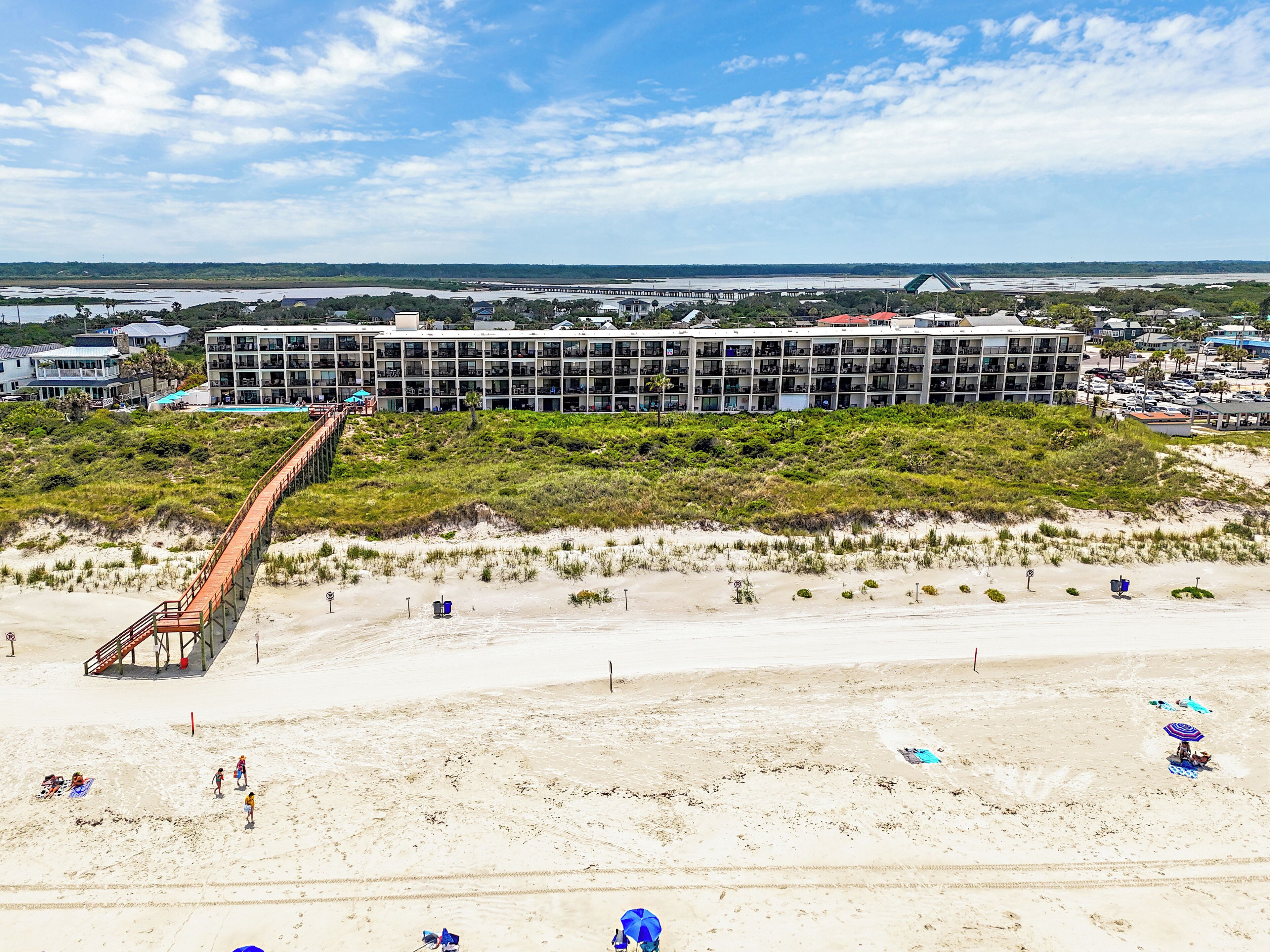 Un hotel sulla spiaggia con un lungo molo, una spiaggia sabbiosa e vista sull'oceano.