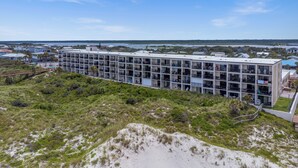 A modern multi-story hotel with a flat roof and balconies, surrounded by natural landscape and a view of the sea. - Beacher's Lodge Oceanfront Suites (St. Augustine)