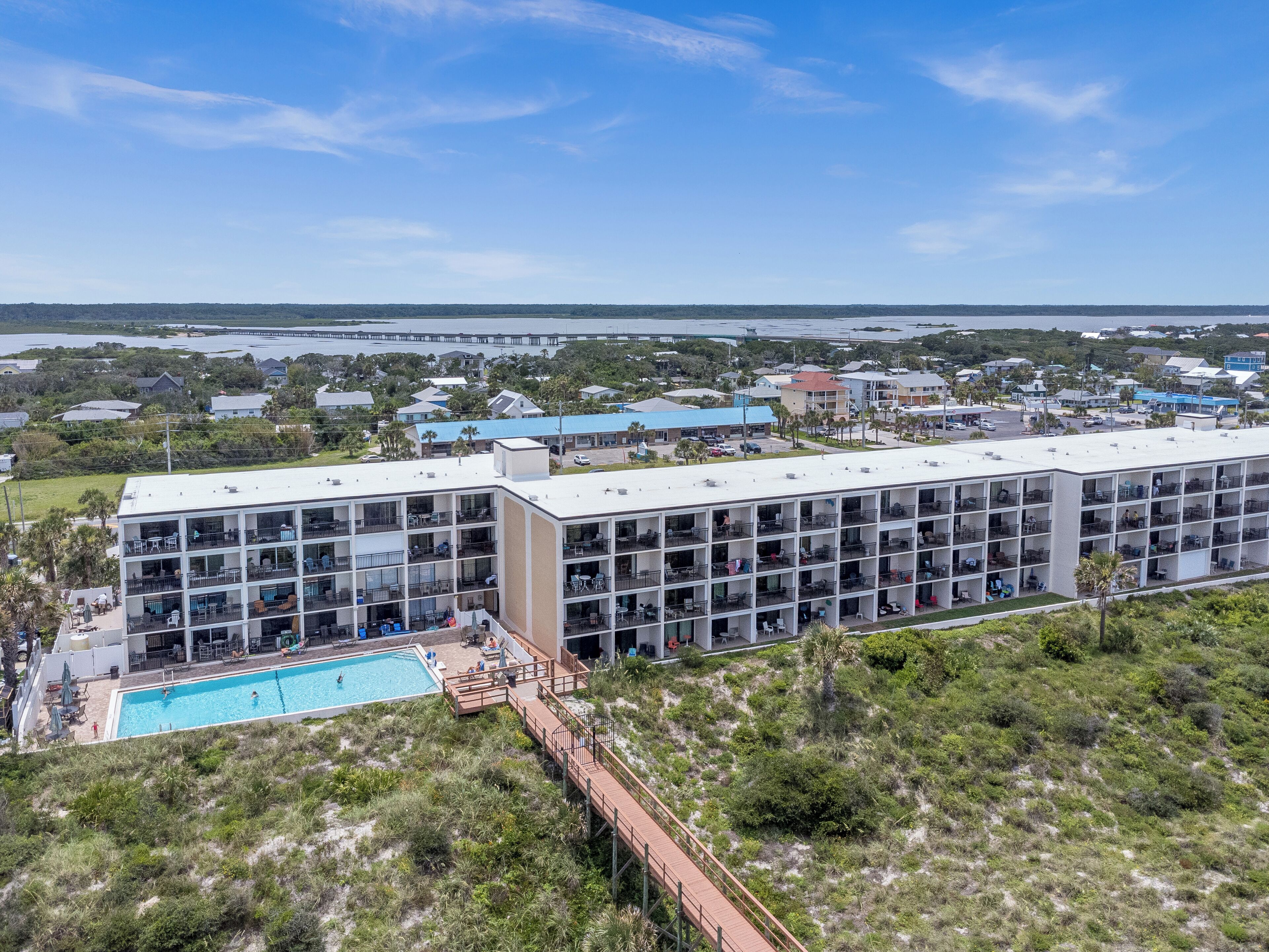 Un hotel moderno con varios pisos, una piscina y vistas del entorno.