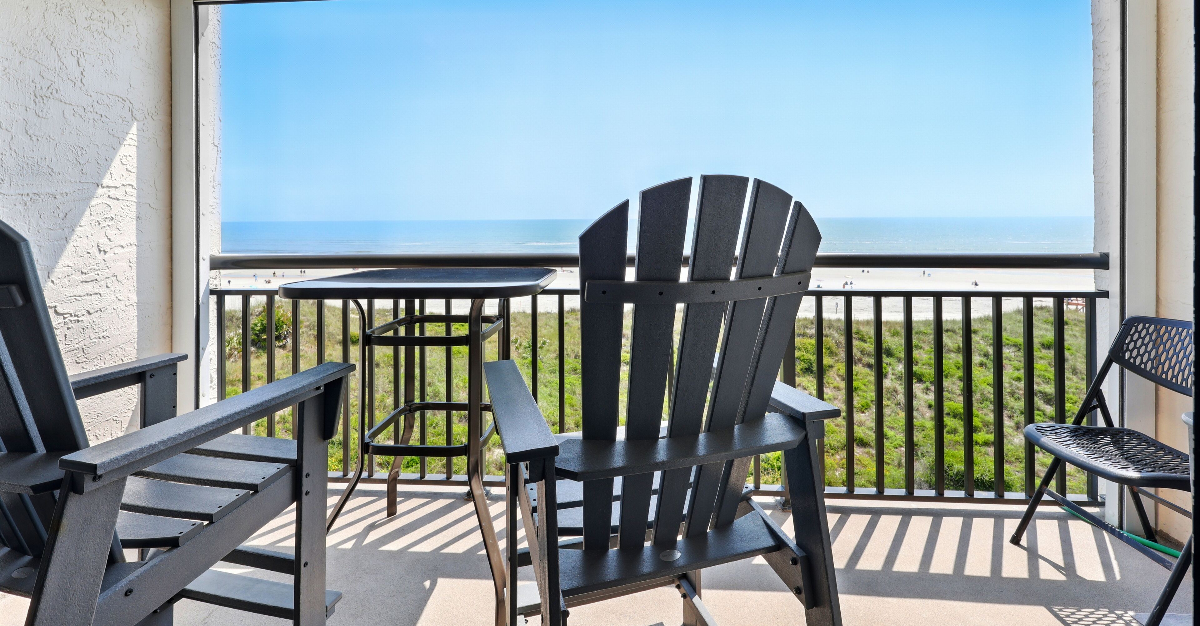 Un balcone con vista sull'oceano, con due poltrone Adirondack e un tavolino.