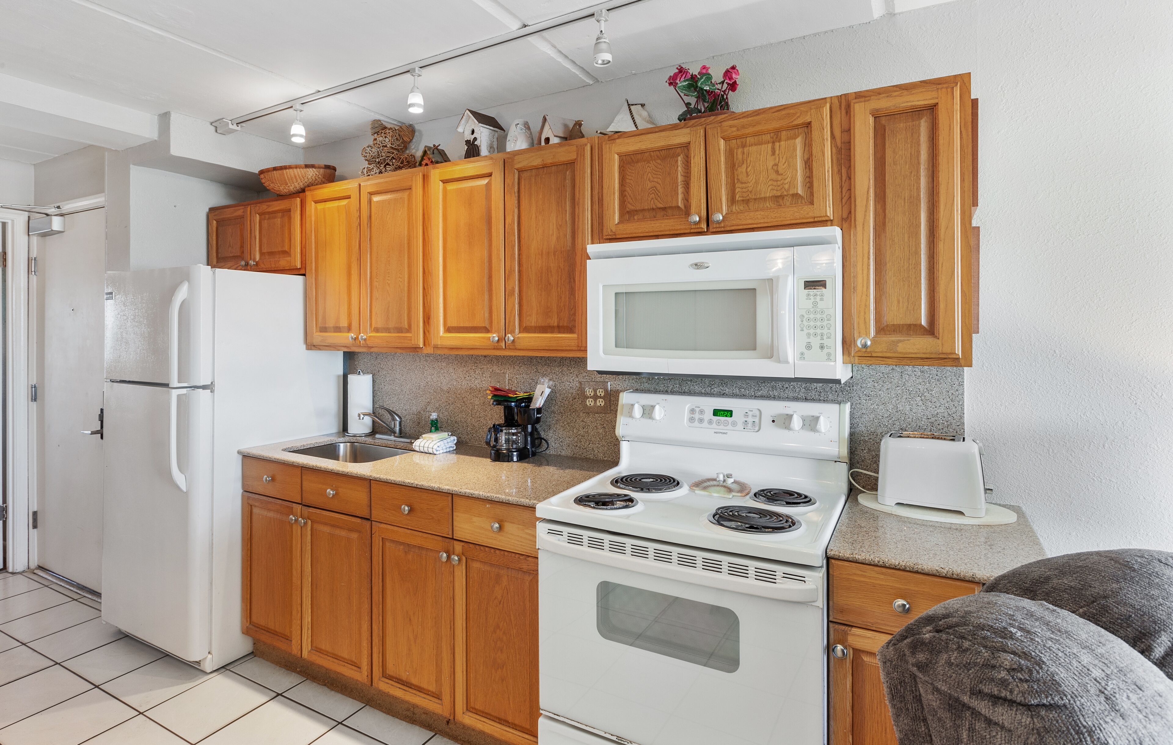 Una cocina con armarios de madera, un refrigerador blanco, un microondas, una estufa y un tostador.