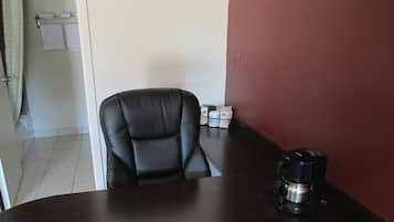 Una sala de conferencias con una silla de cuero negro, una mesa de madera y una cafetera.