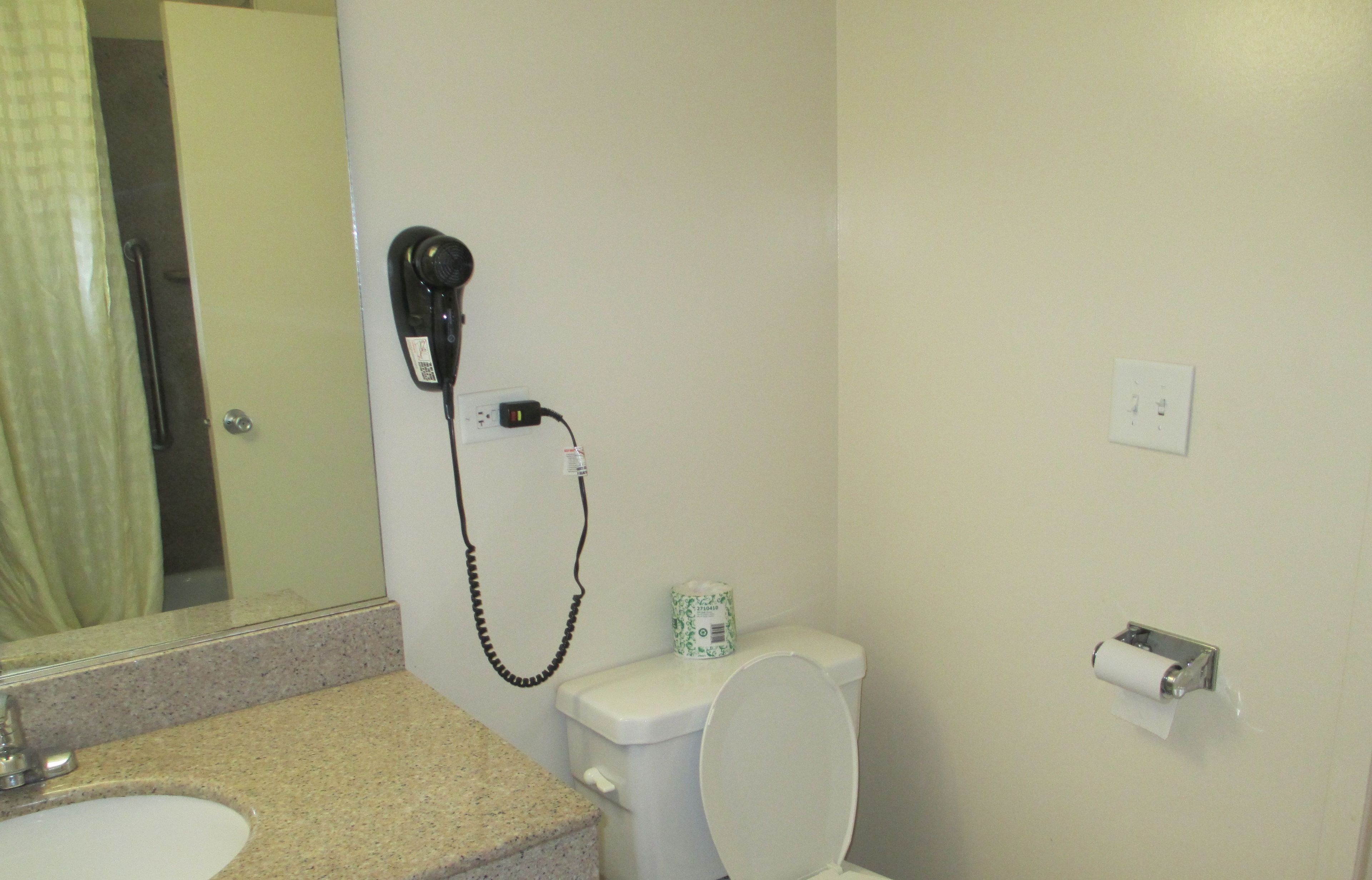 A bathroom with a sink, toilet, and hairdryer on a wall.