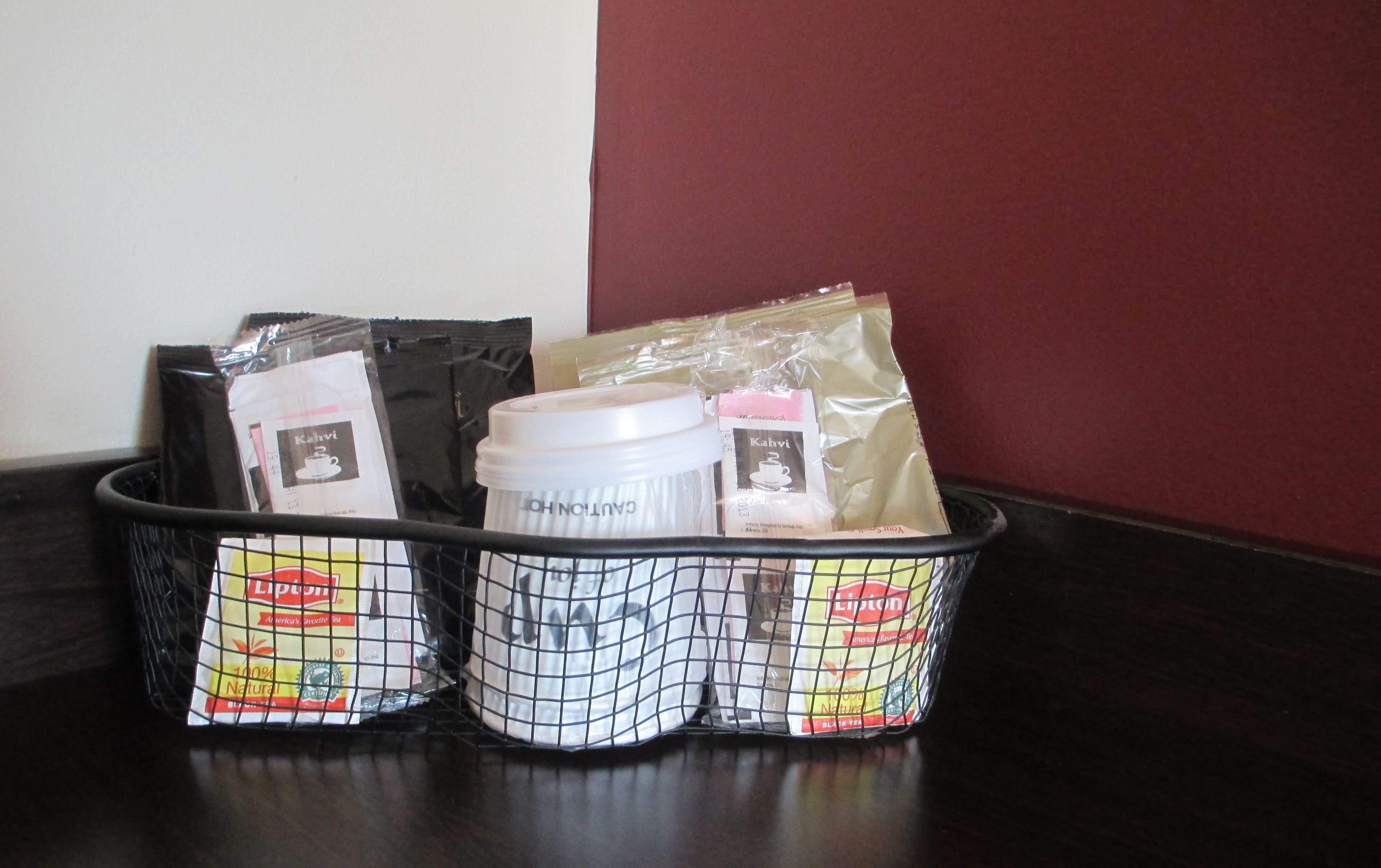 A basket containing various items including a coffee maker, Lipton tea bags, and a bag of coffee.