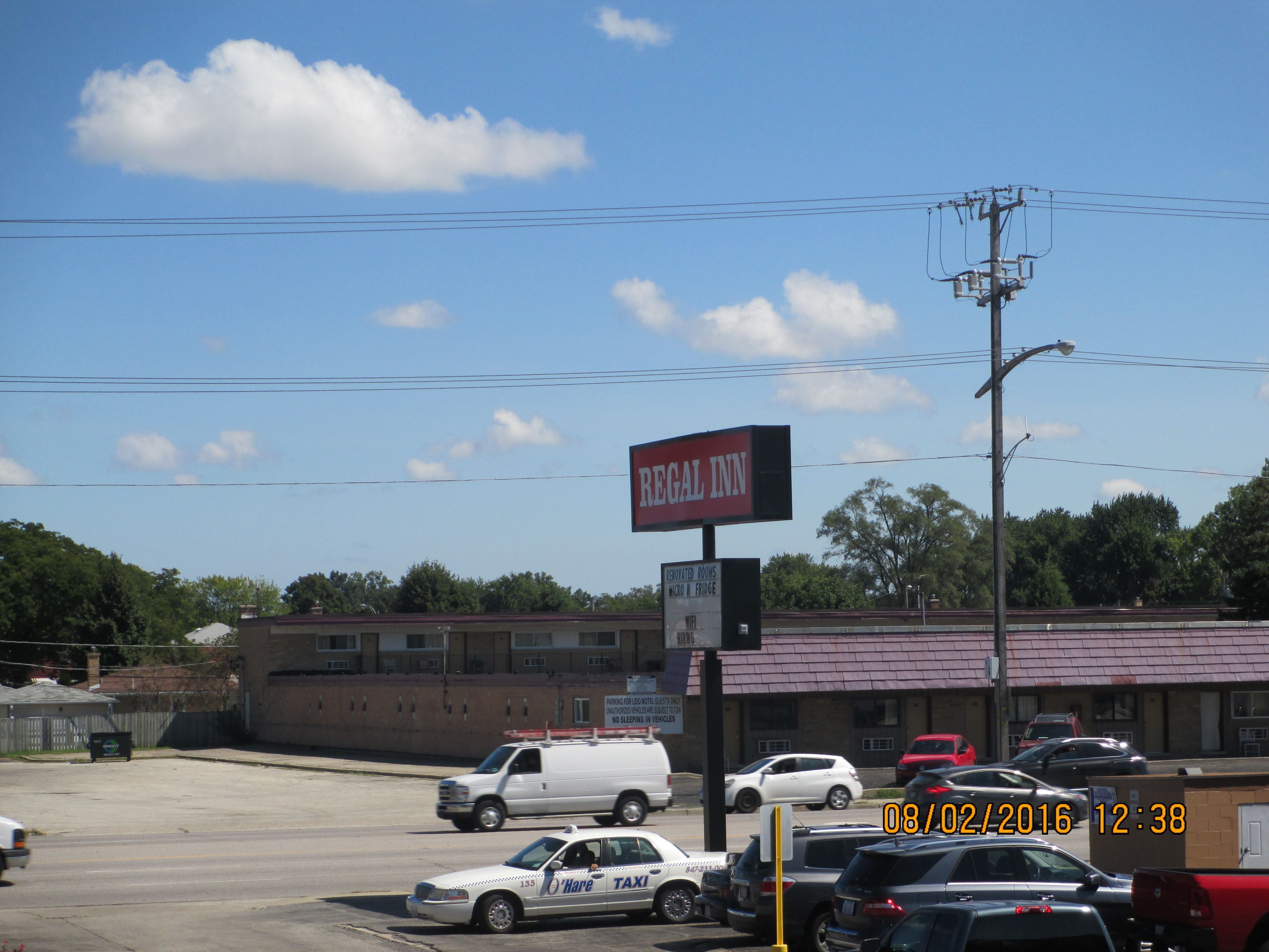 A Regal Inn with a signboard, parking area, and a street view with vehicles.