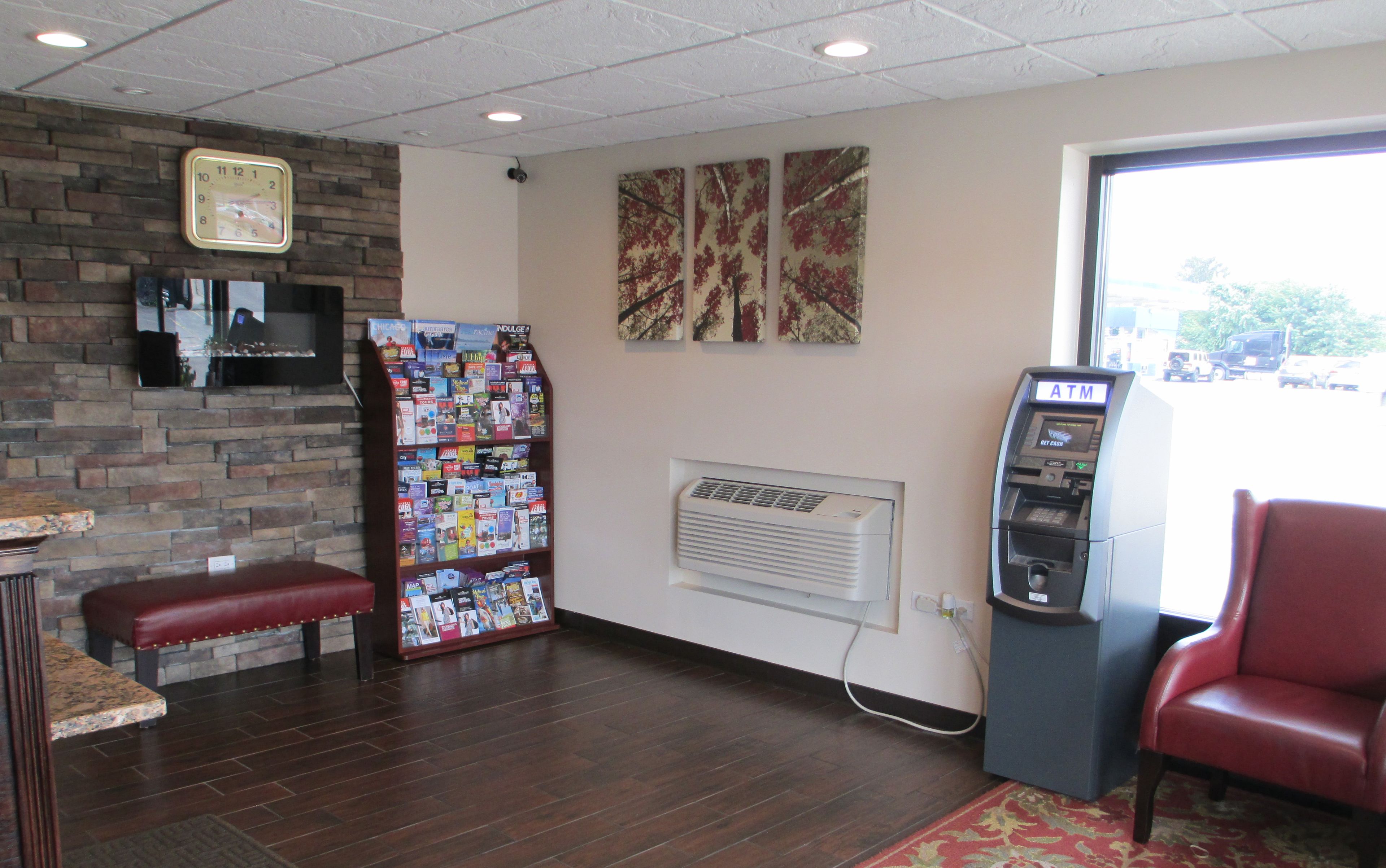 A lobby with a brick wall, a magazine rack, an ATM, and a red leather bench.