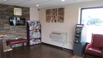 A lobby with a brick wall, a magazine rack, an ATM, and a red leather bench.