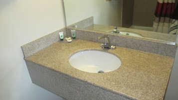 A bathroom with a granite countertop, a white sink, and a mirror.