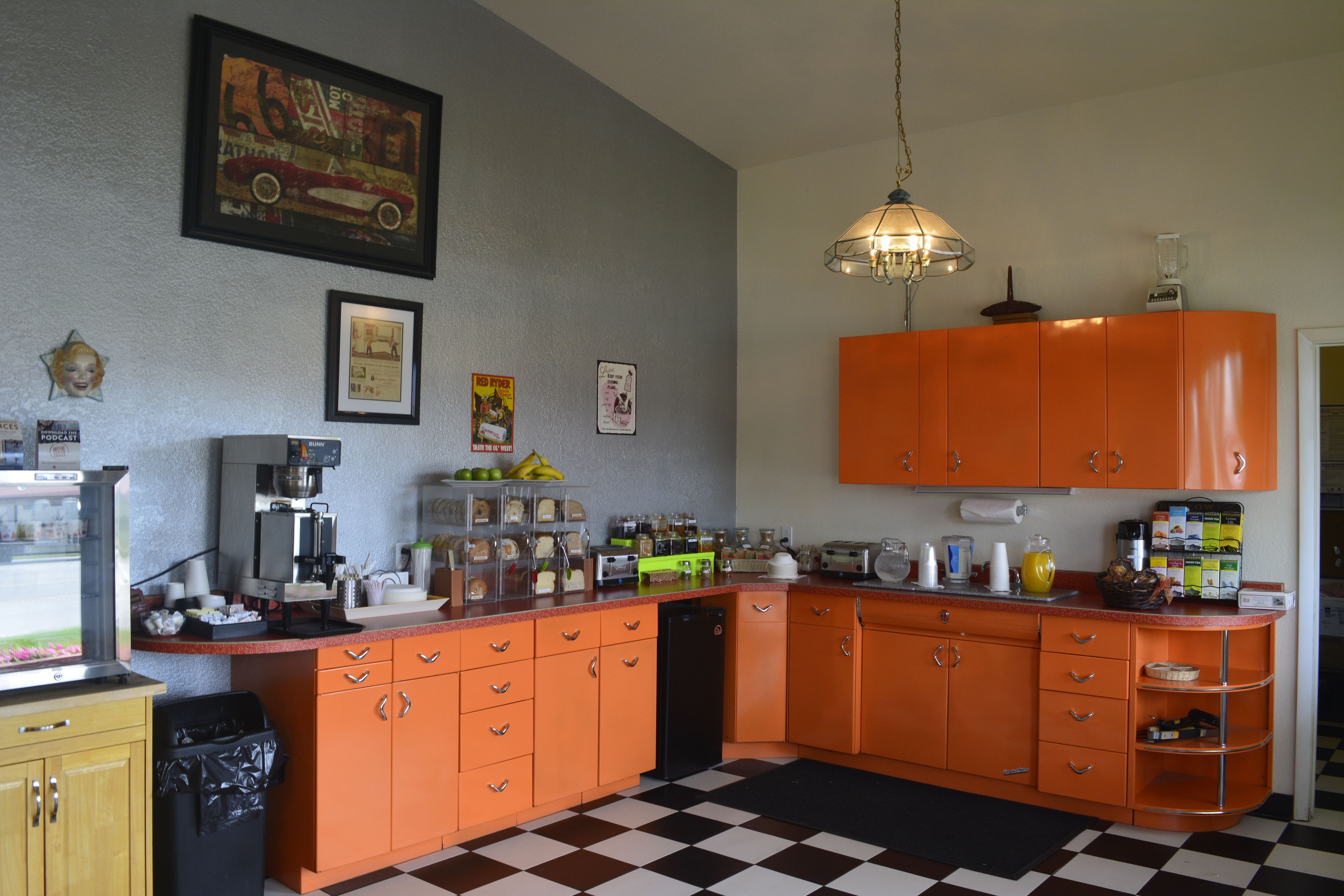 Une cuisine avec des meubles de rangement orange, une machine à café et divers appareils de cuisine.