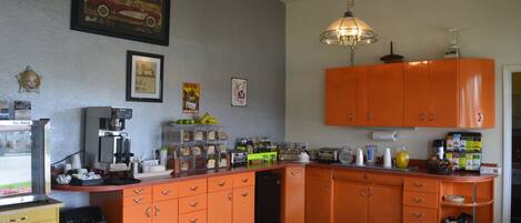A kitchen with orange cabinets, a coffee maker, and various kitchen appliances.