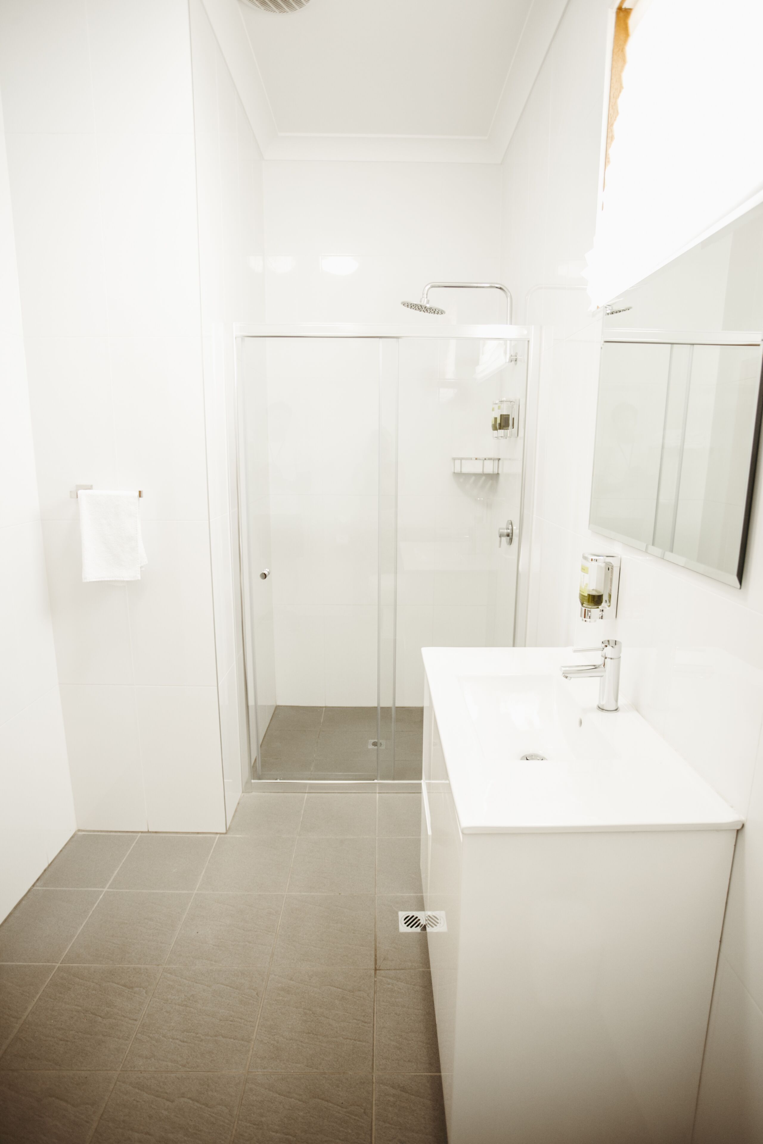 A modern bathroom with a glass shower enclosure, a white sink, and a large mirror.