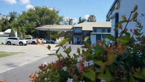 A parking area with several cars, a covered structure, and a building with a flat roof. - Colonial Motel Richmond (Richmond)