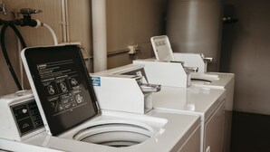 A row of white laundry machines with a digital display in the center, a water tank, and a hand dryer to the right. - Colonial Motel Richmond (Richmond)