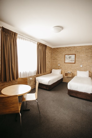 A hotel room with two beds, a round table, and a chair. - Colonial Motel Richmond (Richmond)