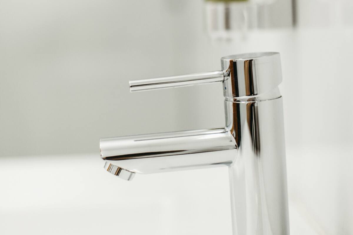 A modern bathroom with a chrome faucet and a soap dispenser mounted on the wall.