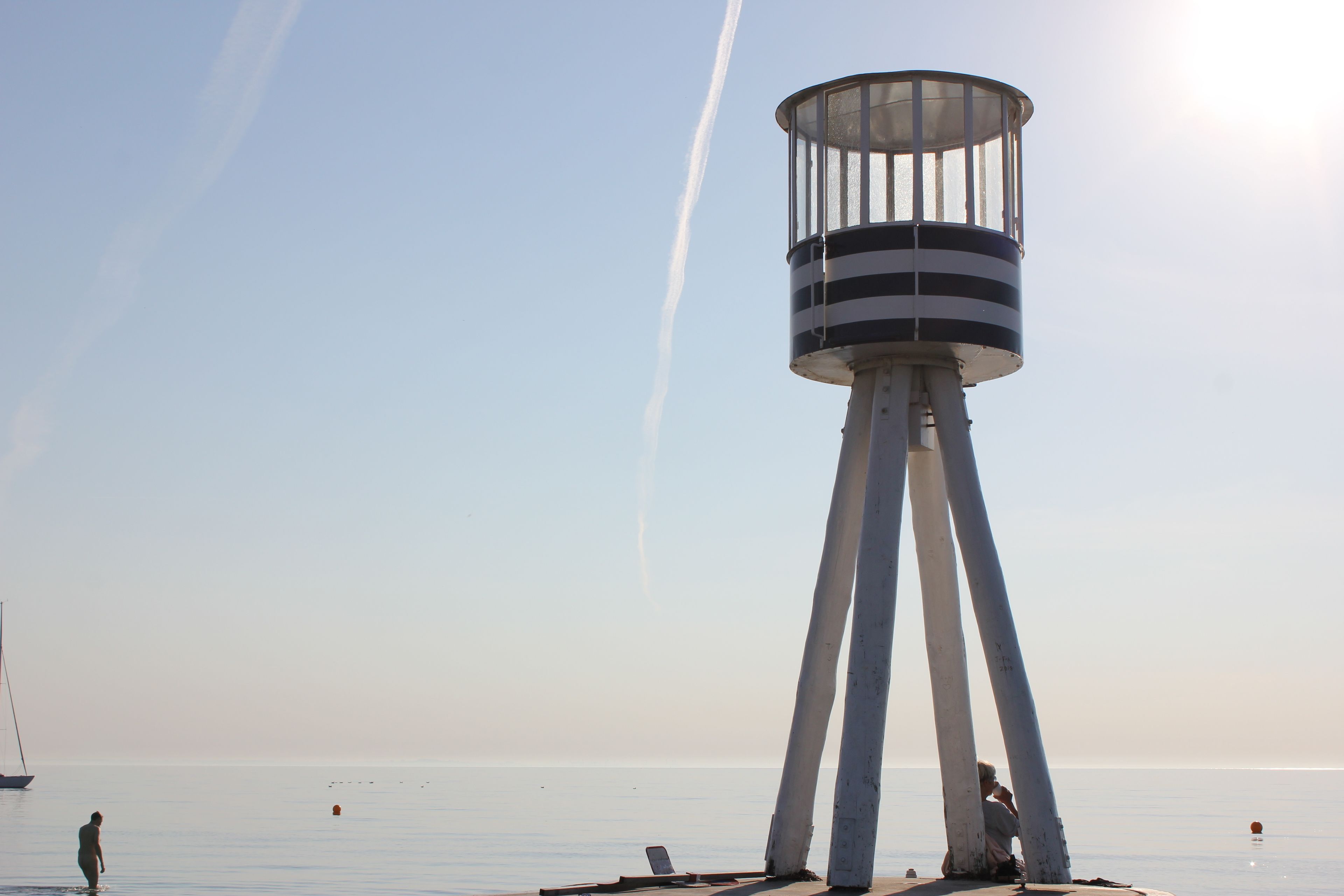 Un faro con una parte superior cilíndrica y una base sostenida por cuatro pilares.