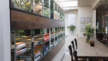 A modern library with bookshelves, a wooden table, and potted plants.