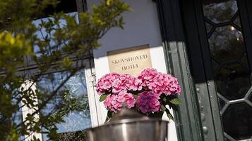 A sign for the Skovshoved Hotel with a large metal pot of pink flowers in front.