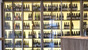 A bar area with multiple stools and a wall of wine bottles. - Skovshoved Hotel (Charlottenlund)