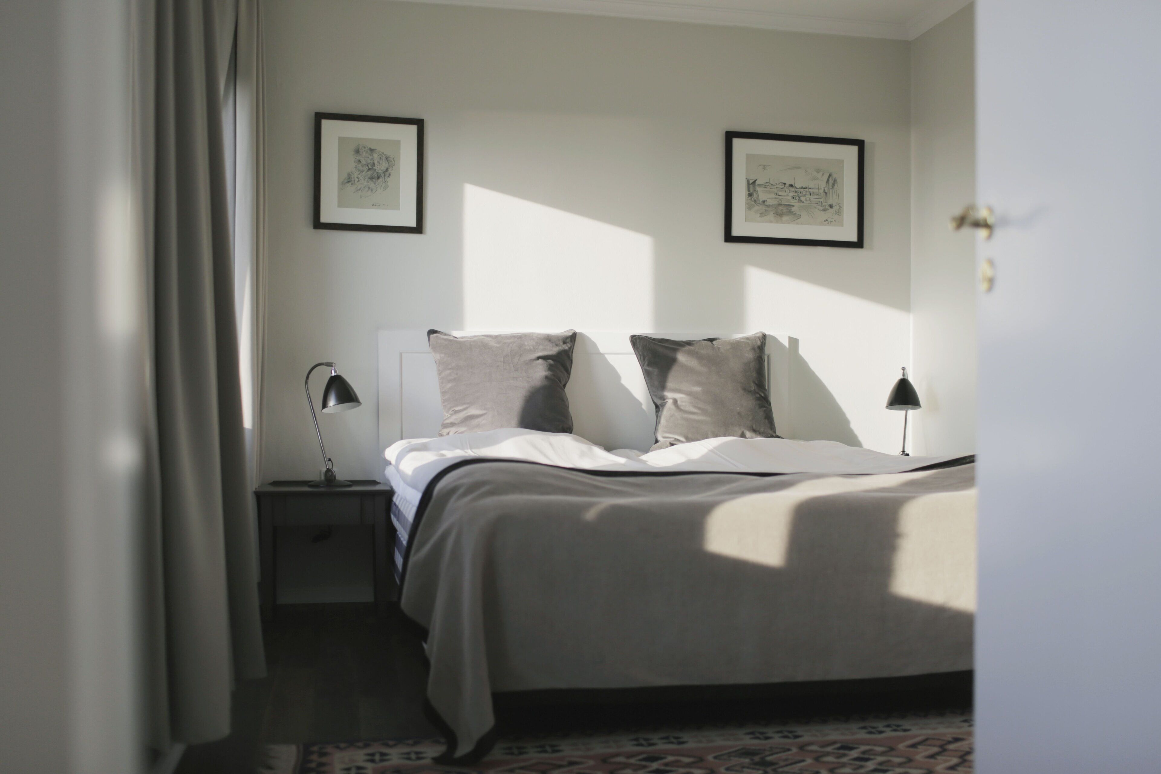 A bedroom with a bed, two bedside tables, and two framed pictures on the wall.