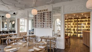 A restaurant with wooden tables and chairs, a wall of wine bottles, and a bar area. - Skovshoved Hotel (Charlottenlund)
