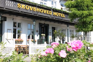 A hotel named "Skovshoved Hotel" with a white facade, a black signboard, and a white picket fence. - Skovshoved Hotel (Charlottenlund)