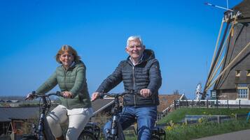 Twee personen fietsen op een pad, met gebouwen op de achtergrond.