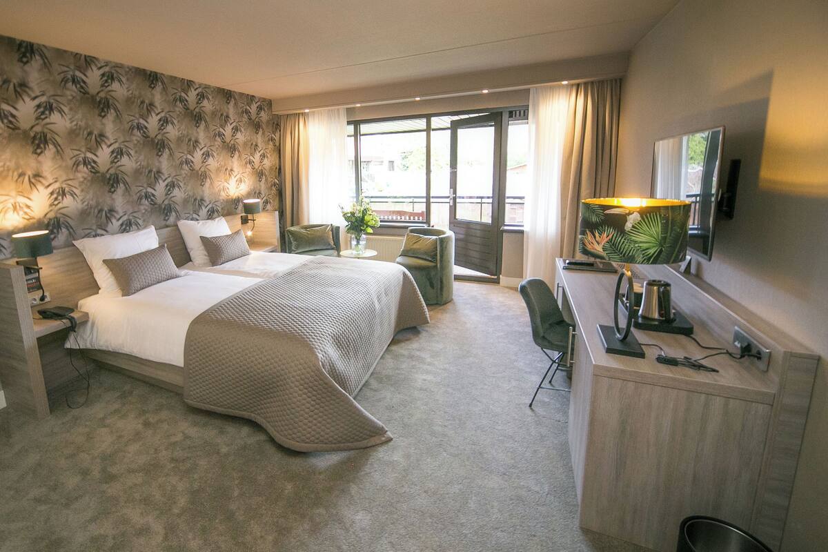 Une chambre d’hôtel avec un lit, un bureau, une chaise et une vue par la fenêtre.