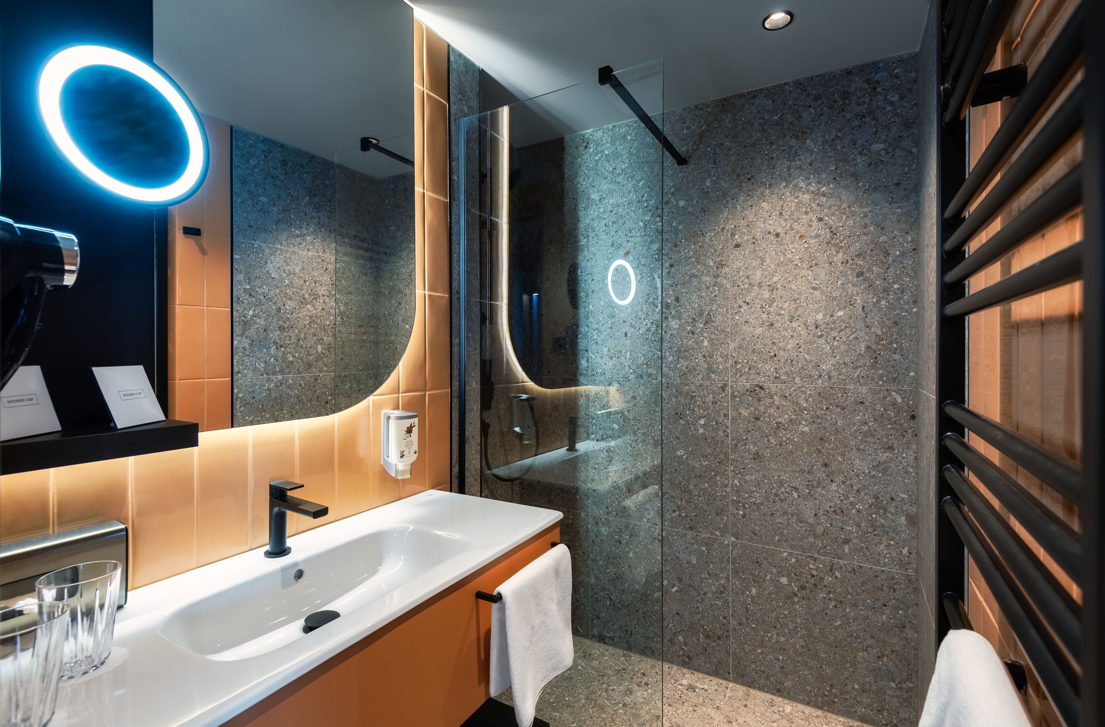 A modern bathroom with a white sink, a glass shower enclosure, and a towel rack.