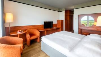 Ett hotellrum med en säng, en TV, ett skrivbord, en stol och en garderob.
