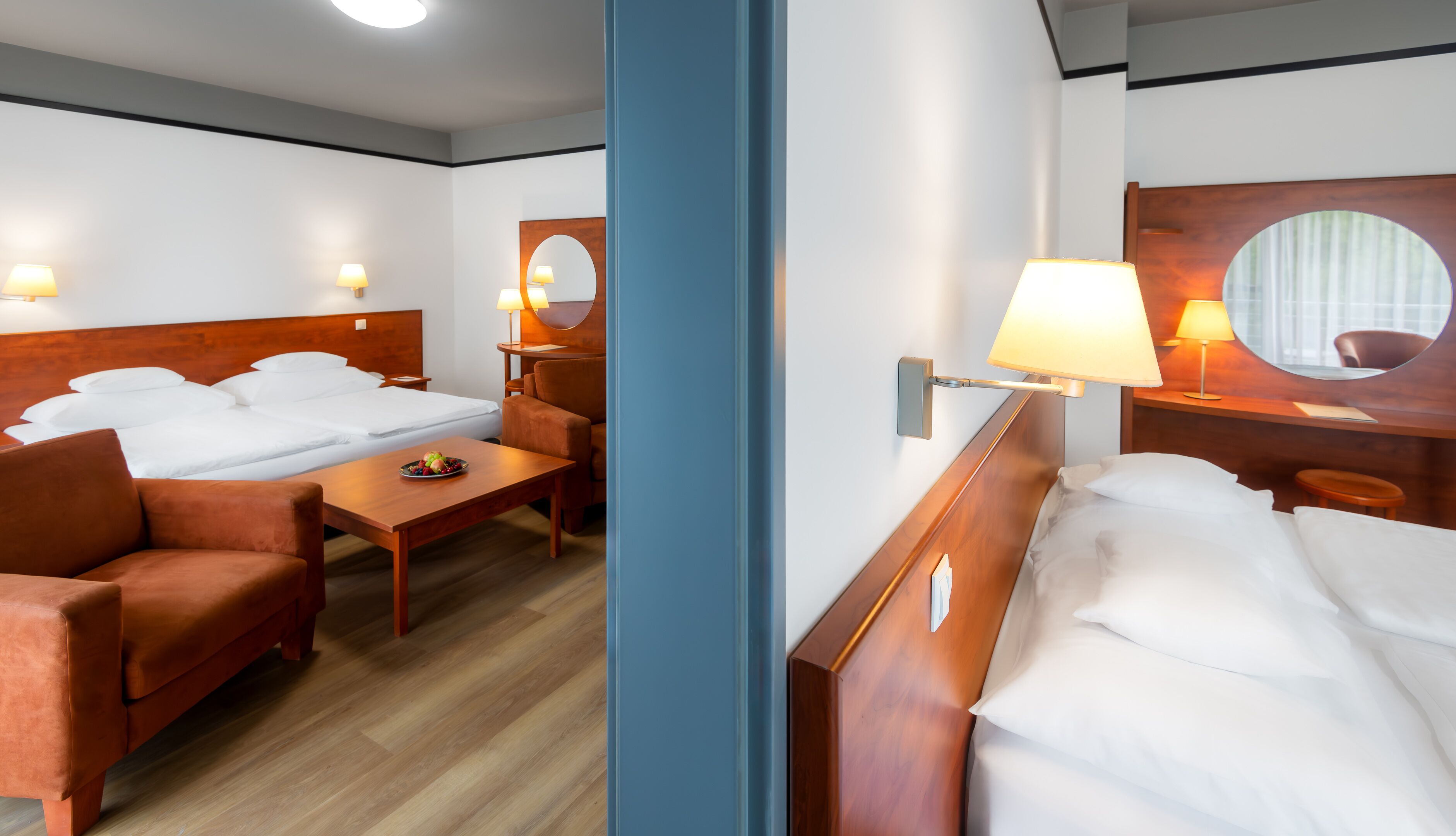 A hotel room with two beds, a desk, a chair, and a mirror.