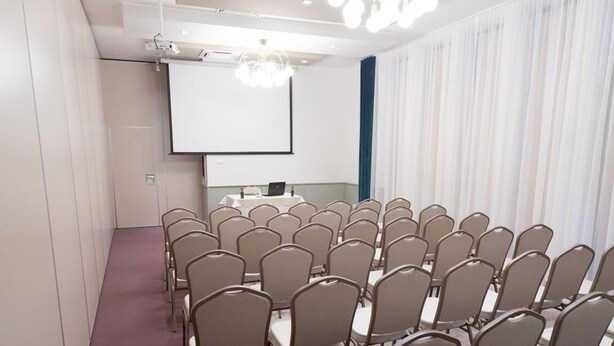 A conference room with rows of chairs, a projector screen, and a whiteboard.