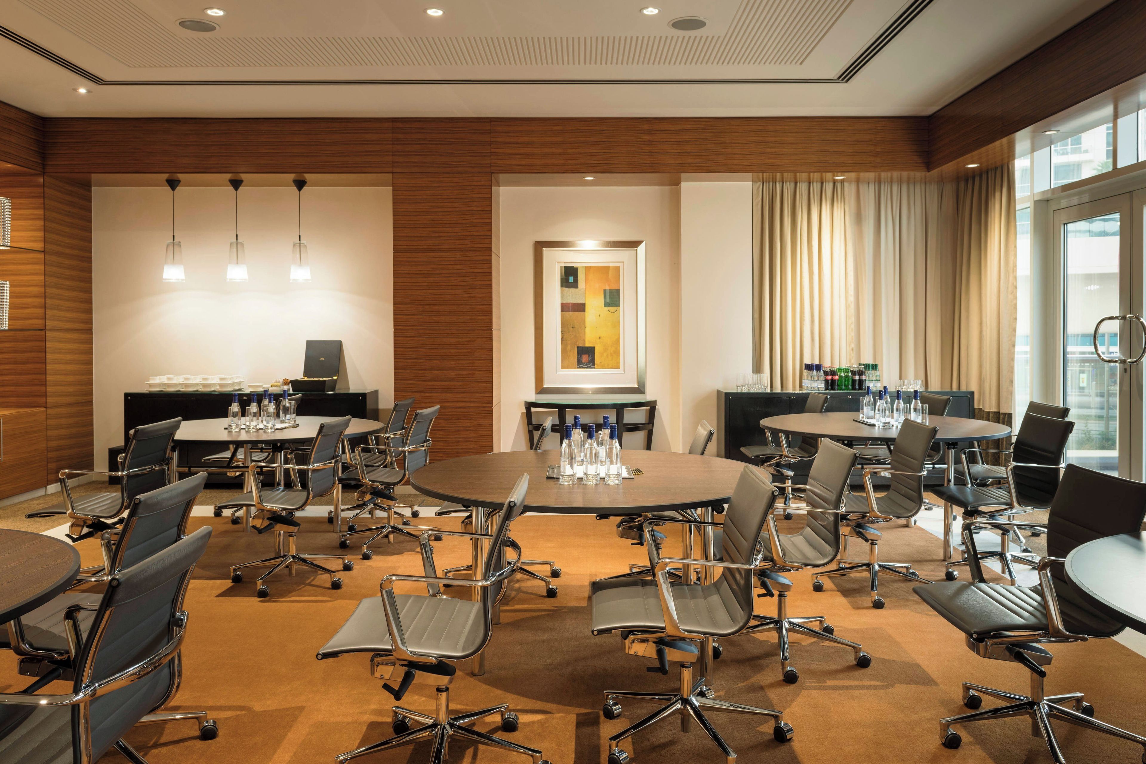 A conference room with round tables, modern chairs, and a large window with curtains.