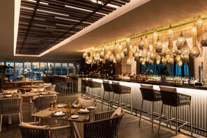 A modern bar area with high stools, a long counter, and hanging decorative lights. - Grosvenor House, a Luxury Collection Hotel, Dubai (Dubai)