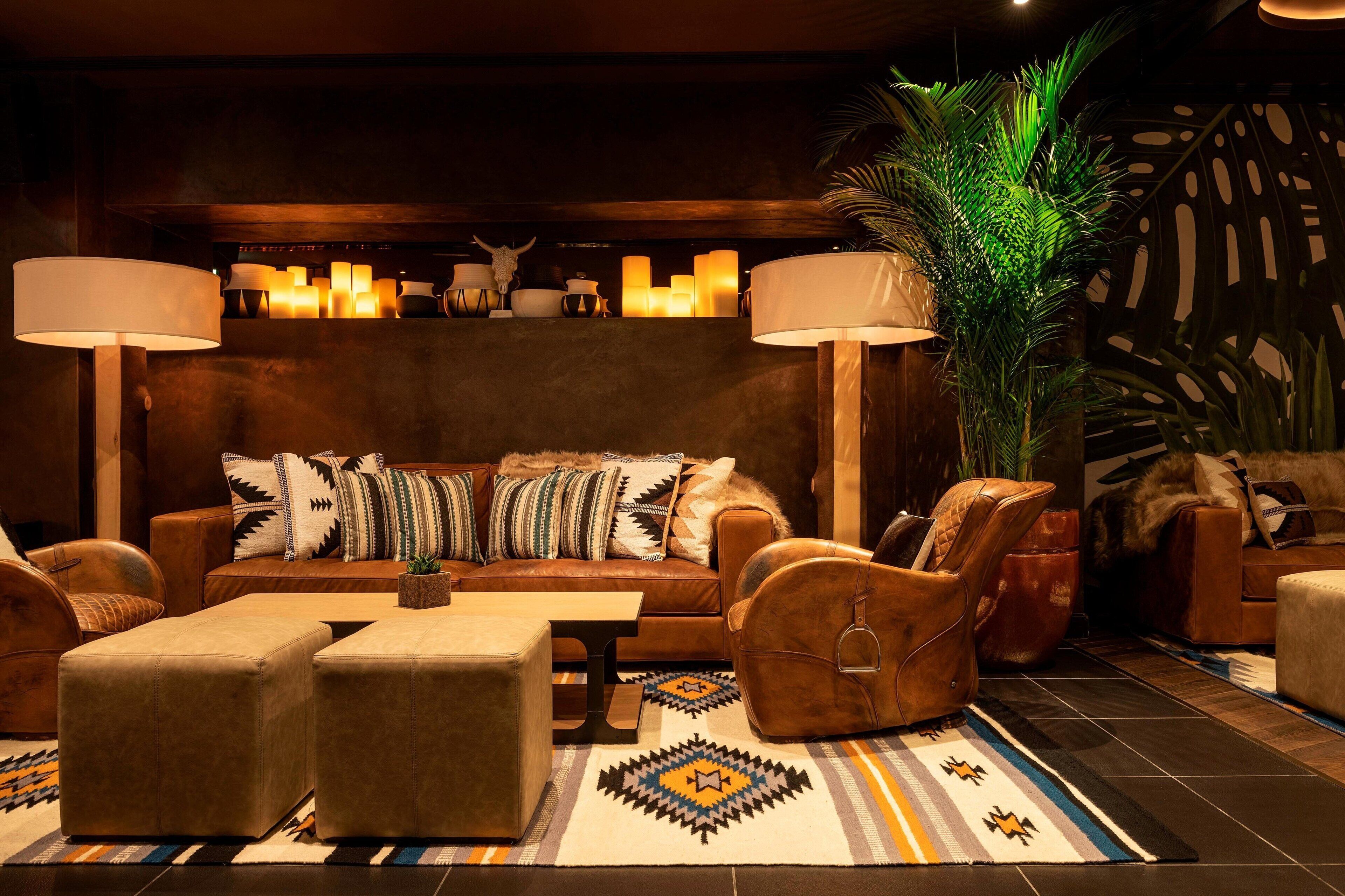 Ein gemütlicher Lounge-Bereich mit Ledersofa, Sesseln und einem gemusterten Teppich.