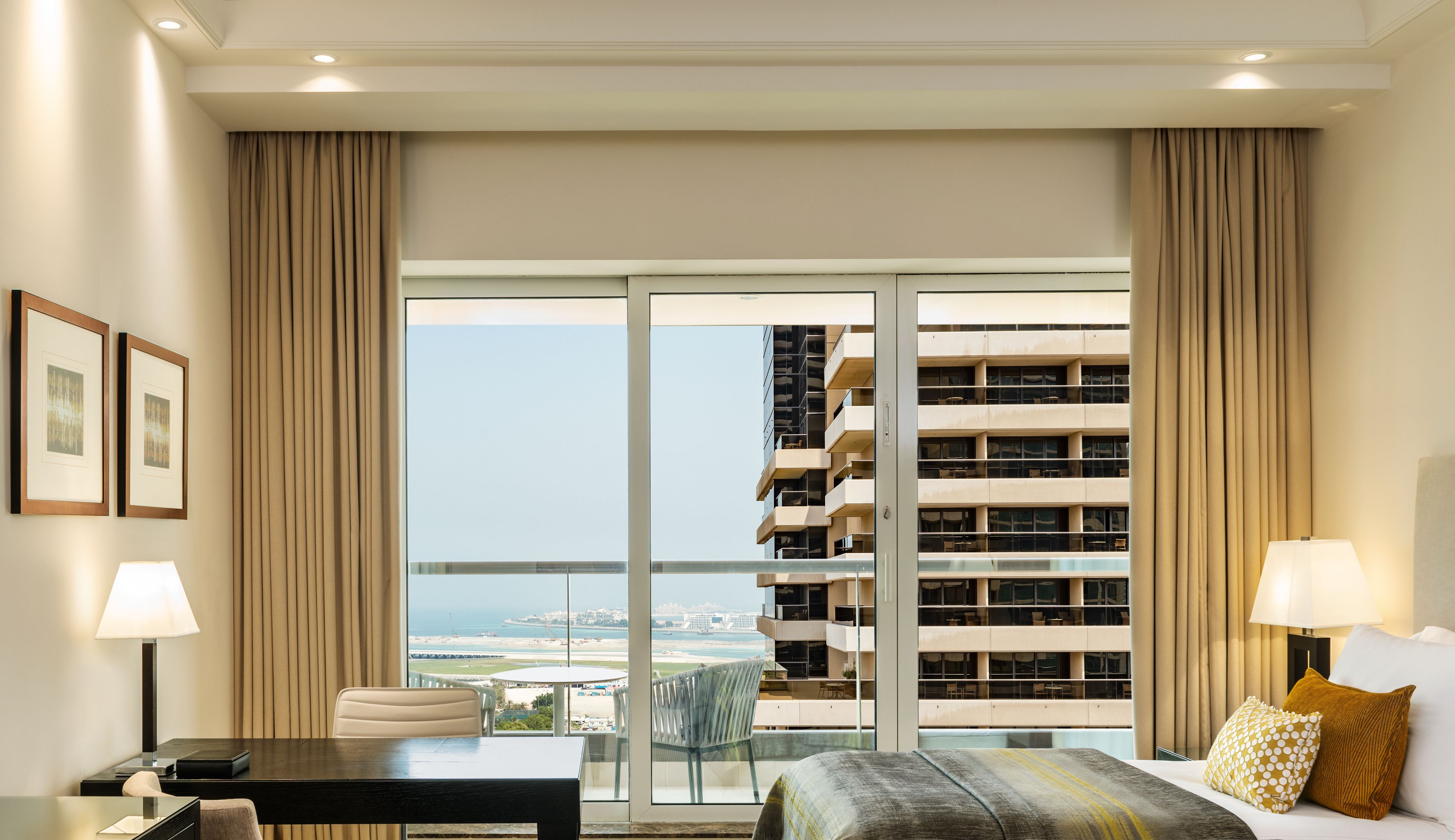 Una habitación de hotel con un ventanal grande, una cama, un escritorio y una silla.