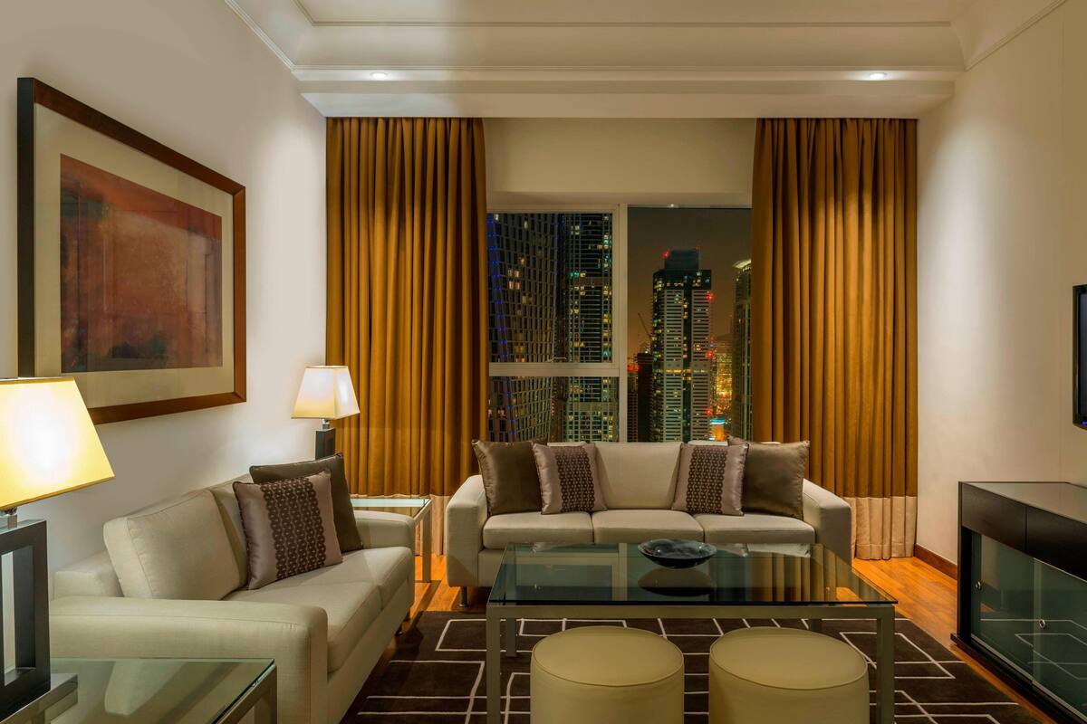 A modern living room with a sofa, two lamps, a glass coffee table, and a TV.