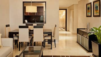 A modern living room with a dining area, a kitchen, and a hallway leading to a bedroom.