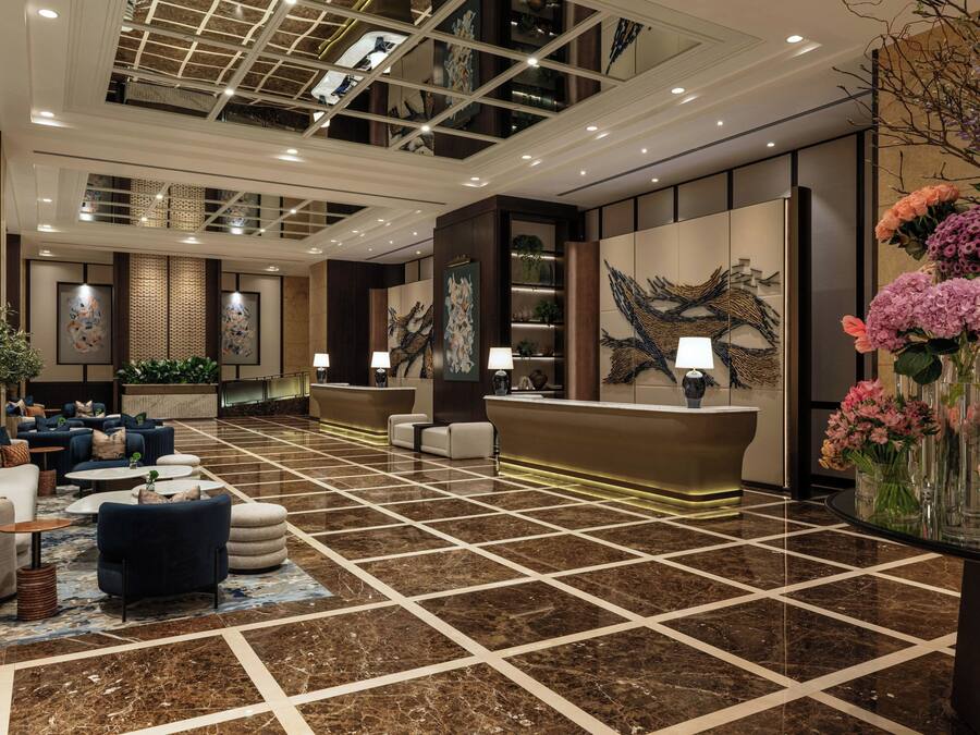 Un hall de hotel con mostrador de recepción, zona de estar y decoración mural.