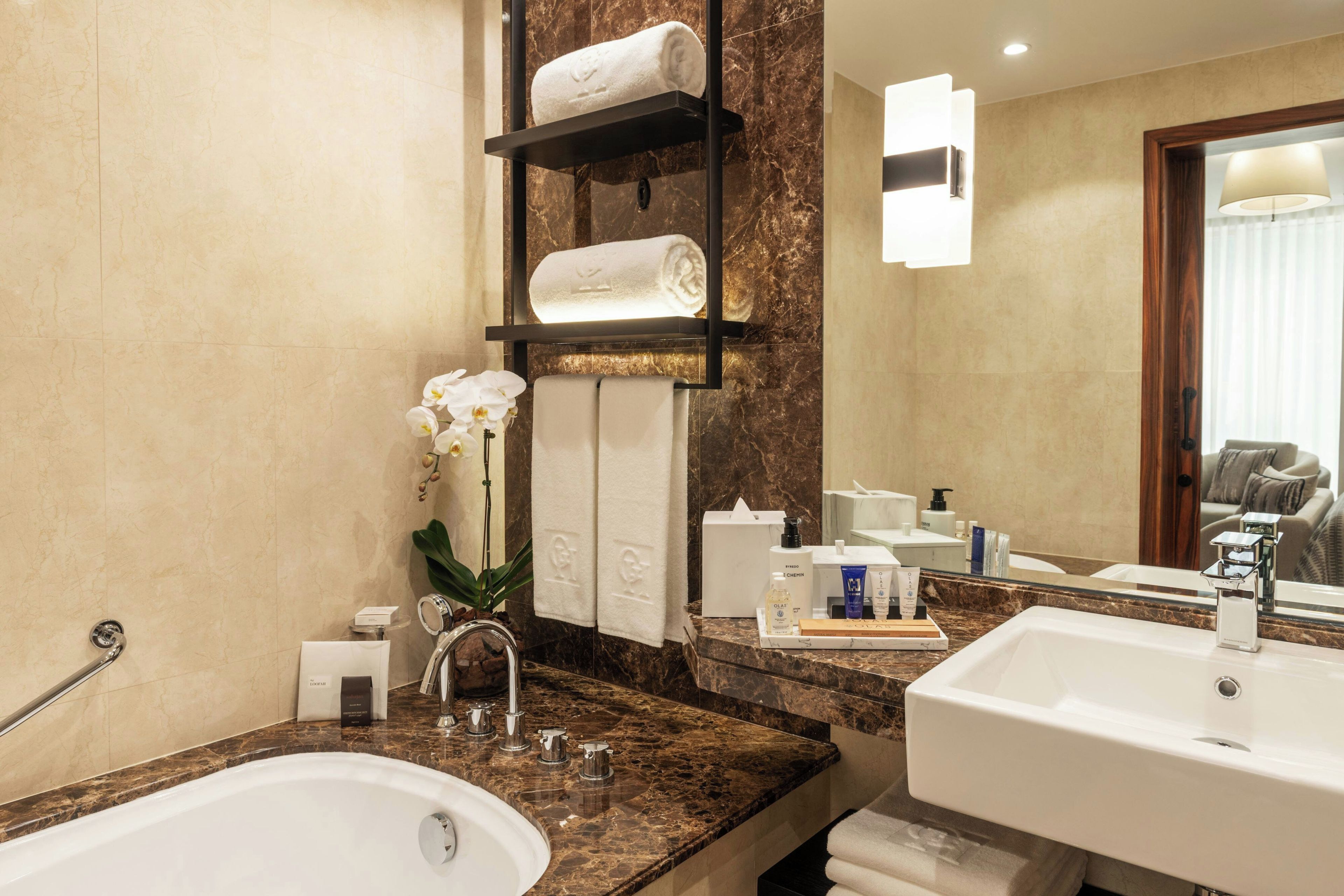 A modern bathroom with a marble countertop, a sink, a mirror, and a towel rack.
