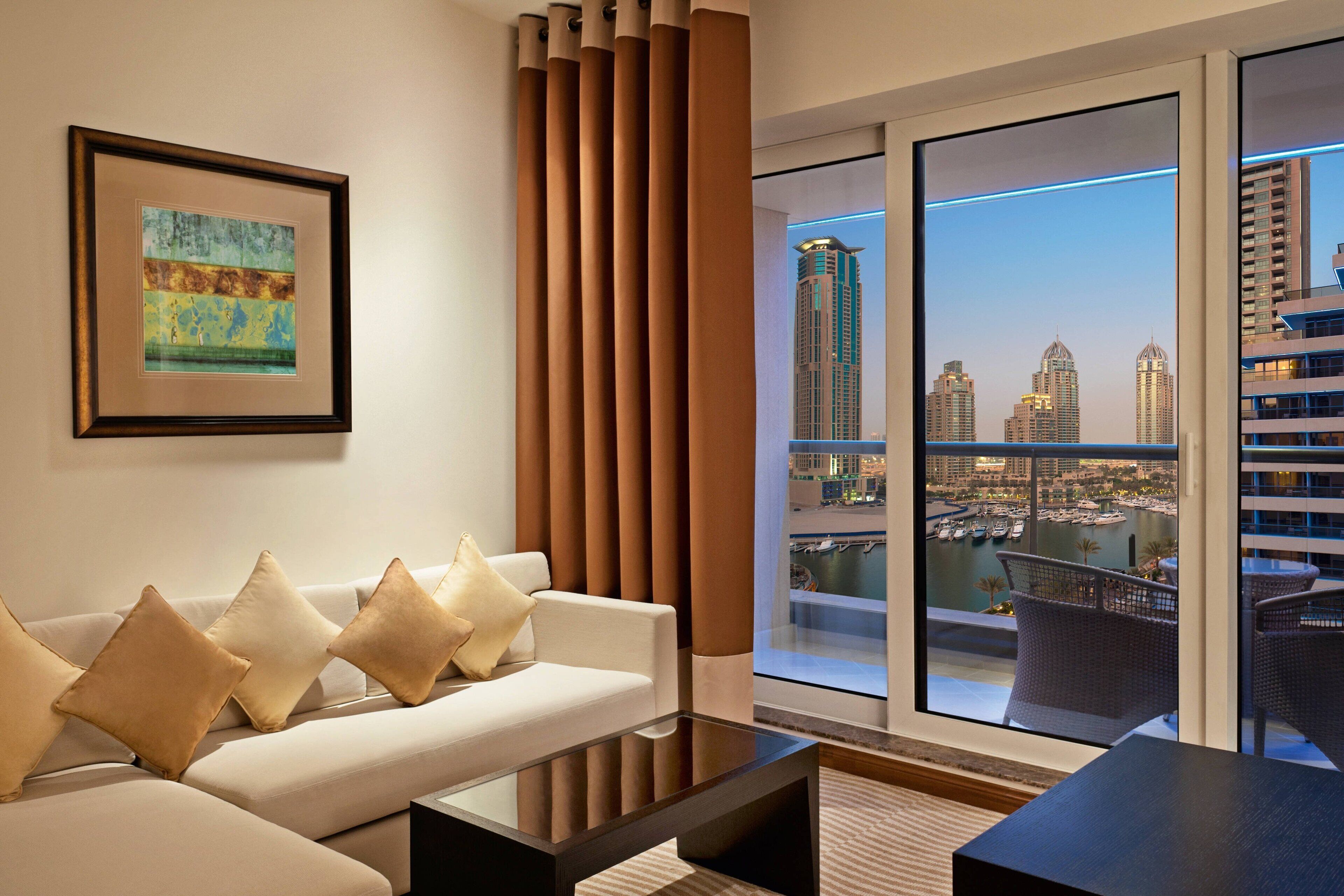A modern living room with a sofa, a coffee table, and a large window offering a city view.