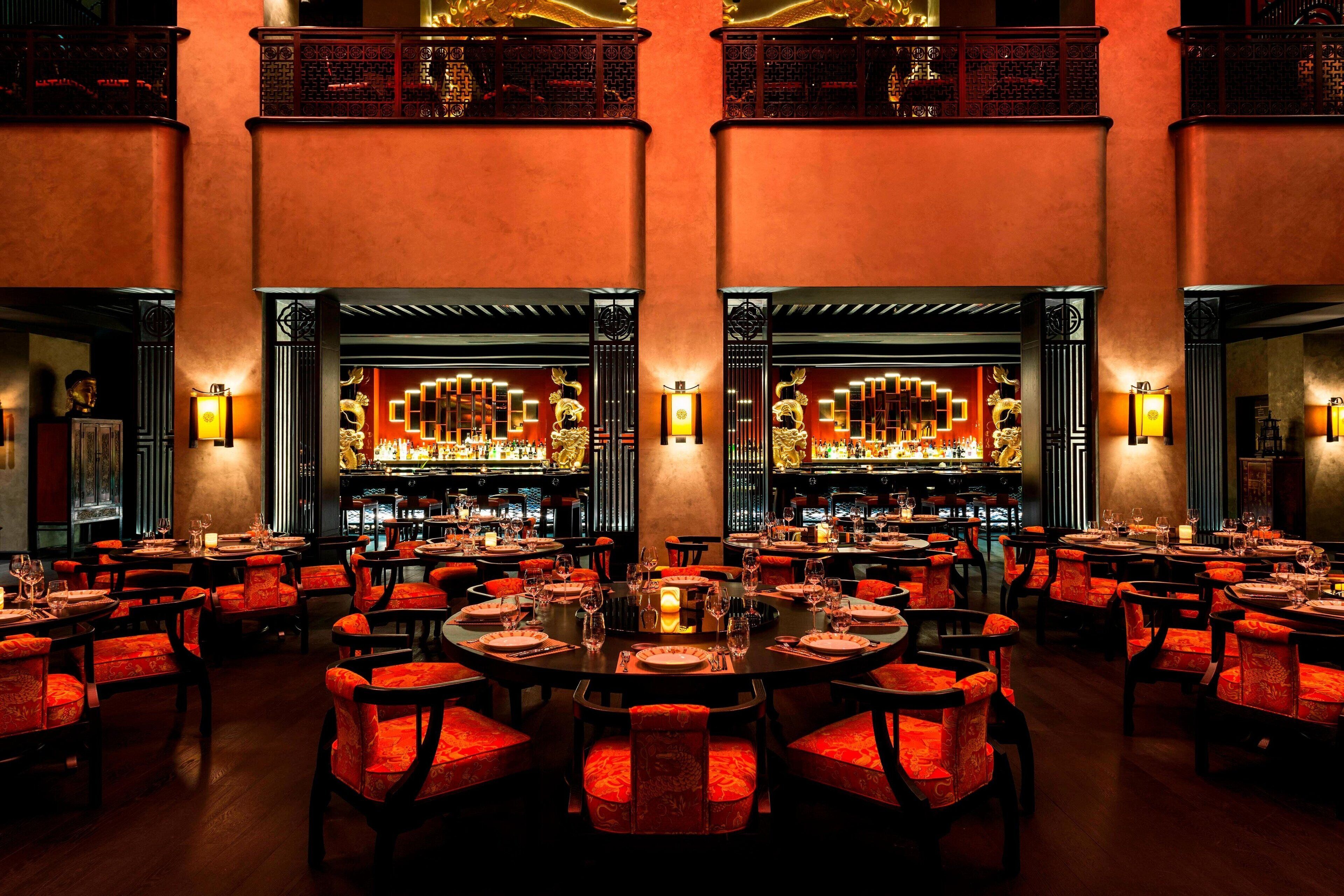 A restaurant with multiple dining tables and chairs, a bar area, and traditional decor.