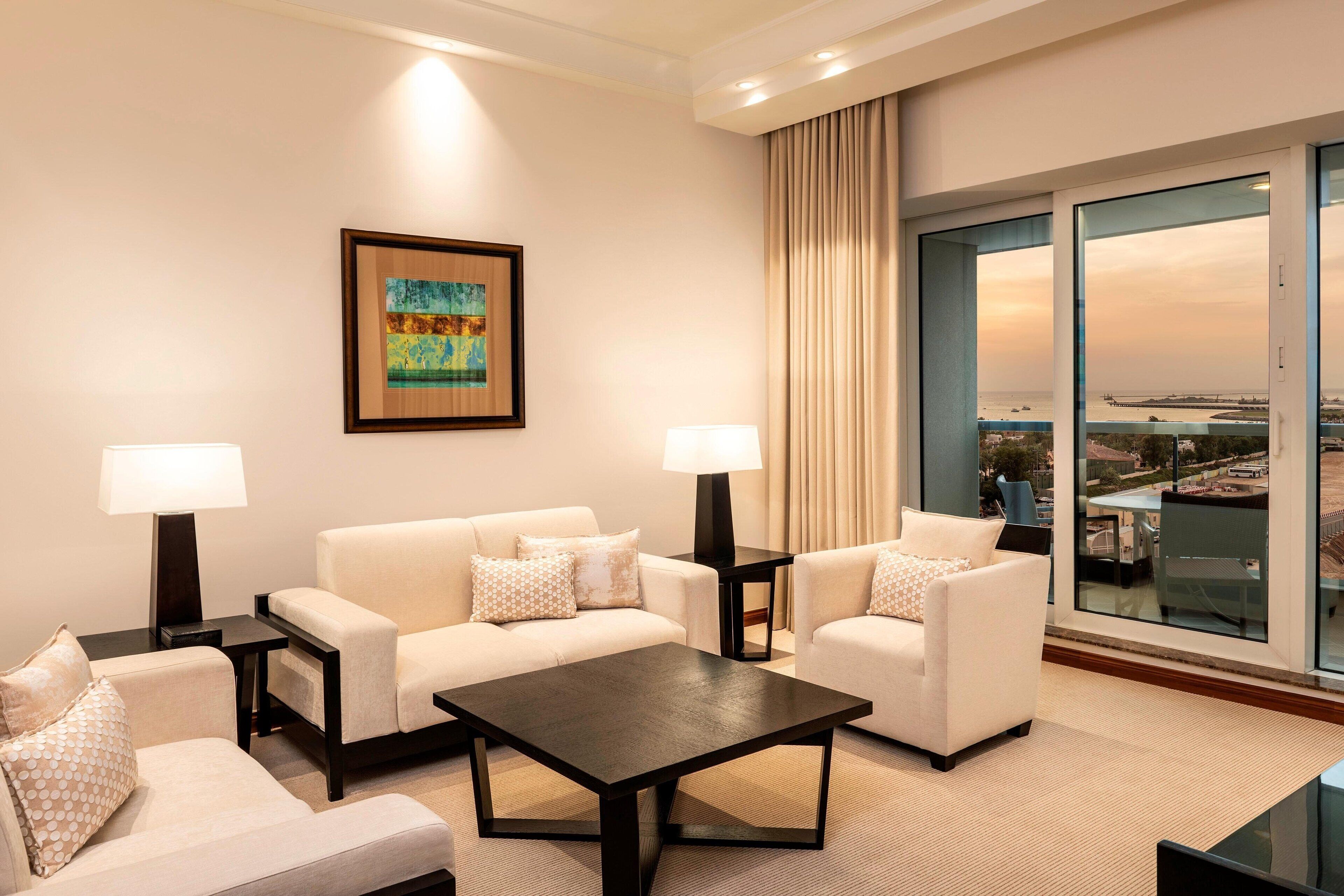 Habitación de hotel con sofá, una mesita de centro y un ventanal con vistas a la ciudad.