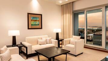 A hotel room with a sofa set, a coffee table, and a large window with a view of the cityscape.