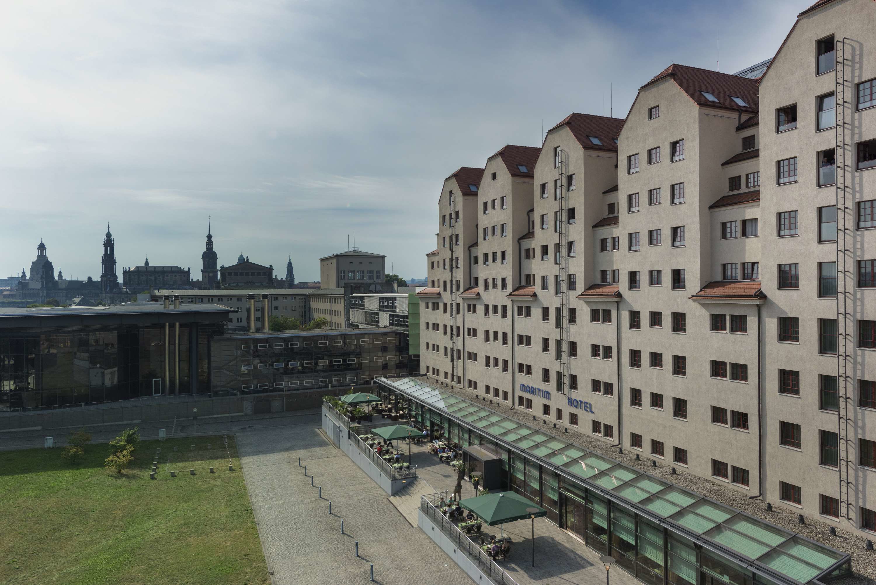 Un hotel con diversi piani, una zona esterna coperta con posti a sedere e vista sullo skyline della città.