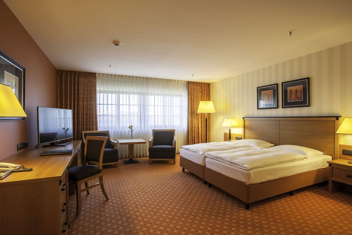 A hotel room with a bed, desk, chair, television, and two lamps.
